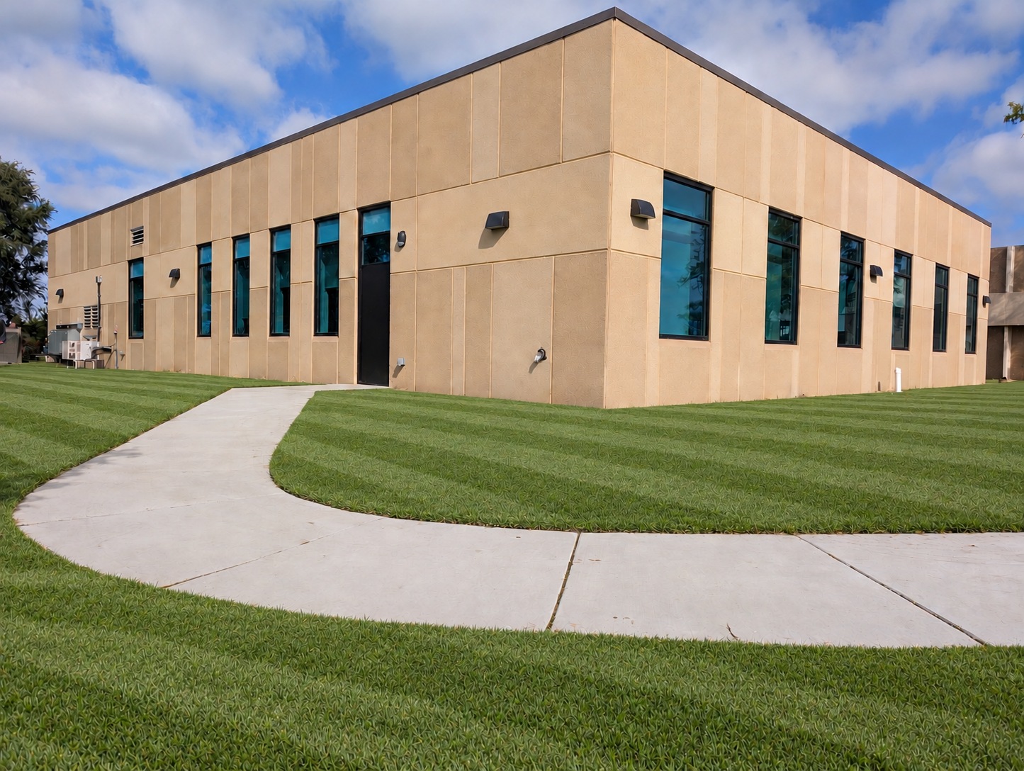 New Fort Thompson Health Center addition with tan exterior panels, tall windows, and a curved concrete walkway